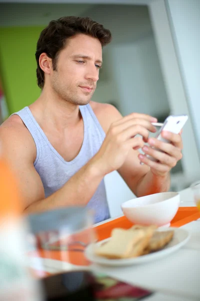 아침 식사 하는 동안 스마트폰 사용 하는 사람 — 스톡 사진
