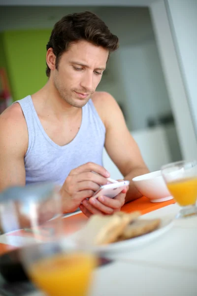 Чоловік використовує смартфон під час сніданку — стокове фото