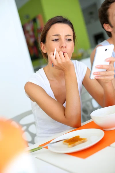 Jovem mulher no café da manhã usando smartphone — Fotografia de Stock