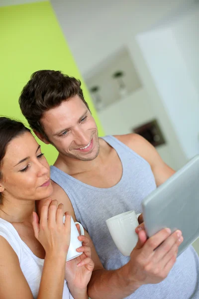 Pareja alegre usando la tableta a la hora del desayuno —  Fotos de Stock