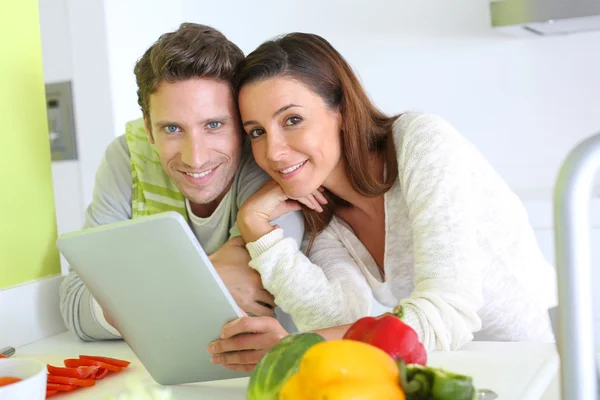 Pareja en casa cocina en busca de receta de almuerzo —  Fotos de Stock