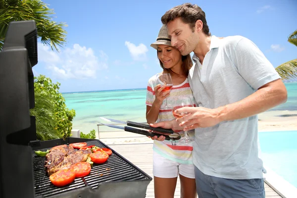 Cheerful couple in holidays preparing grilled meat — Stock Photo, Image