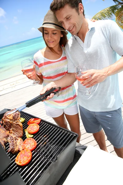 Coppia allegra in vacanza preparando carne alla griglia — Foto Stock