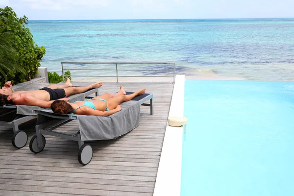 Casal relaxante em cadeiras longas em frente ao mar — Fotografia de Stock
