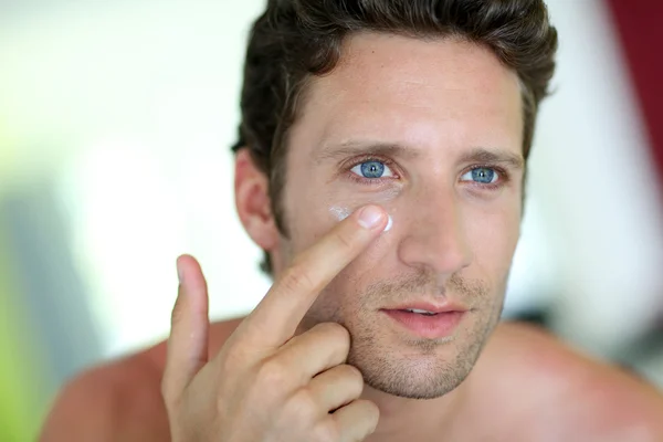 Hombre guapo aplicando crema hidratante — Foto de Stock