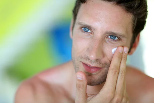 Handsome man applying moisturizing cream — Stock Photo, Image