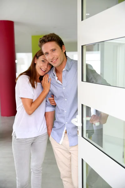 Cheerful couple inviting people to enter in home — Stock Photo, Image