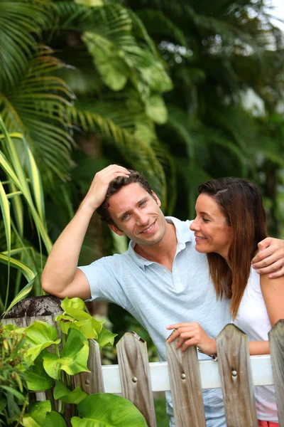 Couple leaning on fence in front of home — Stock Photo, Image