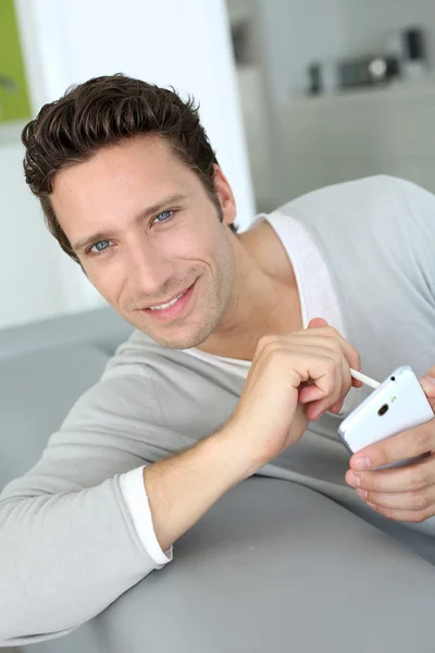 Homme relaxant dans le canapé et la lecture de ses e-mails — Photo