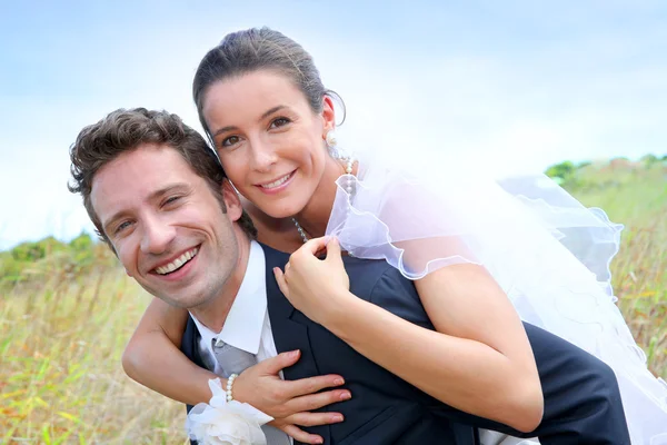 Groom giving pigguback ride to bride — Stock Photo, Image