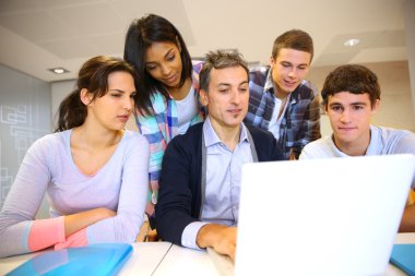 Teacher with students in class working on laptop clipart