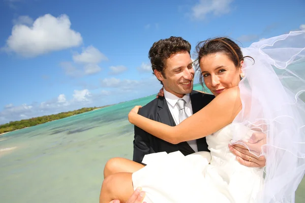 Groom holding his bride by the Caribbean sea — Stock Photo, Image