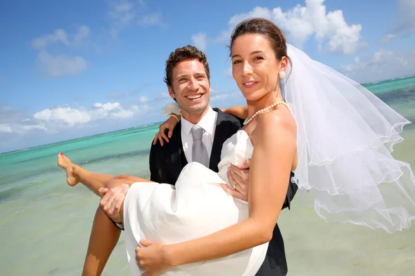 Groom holding his bride by the Caribbean sea — Stock Photo, Image