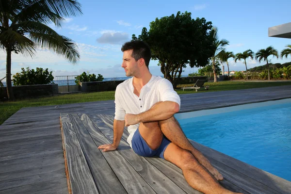 Joven haciendo ejercicios de estiramiento en la terraza de la piscina — Foto de Stock