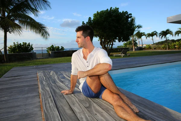 Jovem fazendo exercícios de alongamento no deck da piscina — Fotografia de Stock