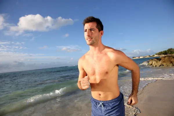 Jeune homme courant sur la plage — Photo