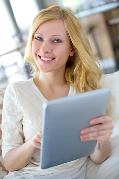 Menina loira sentada no sofá com tablet digital — Fotografia de Stock