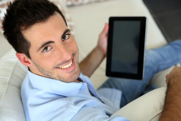 Muž sedící na pohovce pomocí elektronického tabletu — Stock fotografie