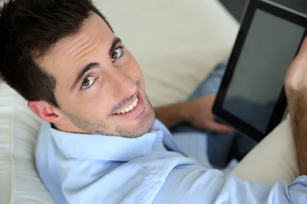 Mężczyzna siedzi w sofie za pomocą tabletu elektronicznego — Zdjęcie stockowe