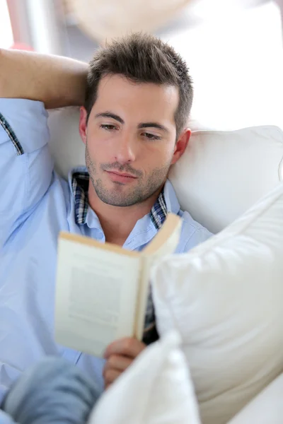 Young man reading book in sofa — Stock Photo, Image