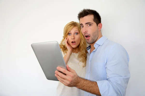 Couple with astonished expression in front of tablet — Stock Photo, Image