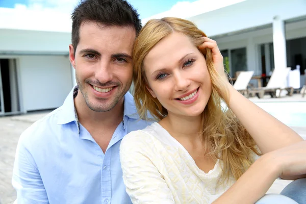 Cheerful young couple sitting in front of modern house — Stock Photo, Image