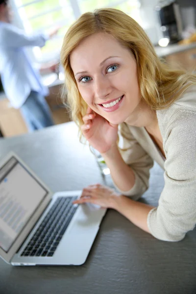 Allegro ragazza bionda collegata su internet in cucina di casa — Foto Stock