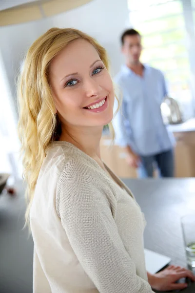 金发碧眼的女人站在厨房，在背景中的人 — 图库照片