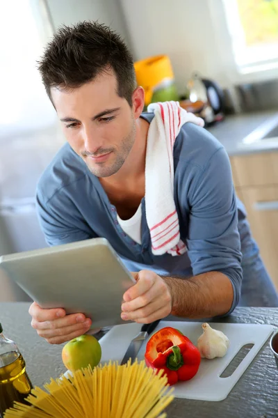 Primer plano del hombre sonriente en la cocina usando la tableta — Foto de Stock