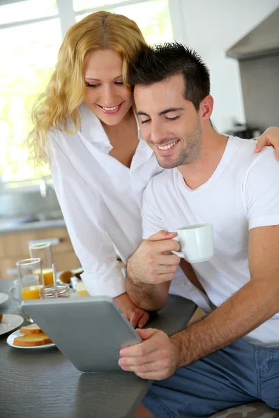 Young couple using digital tablet at breakfast time — Stock Photo, Image