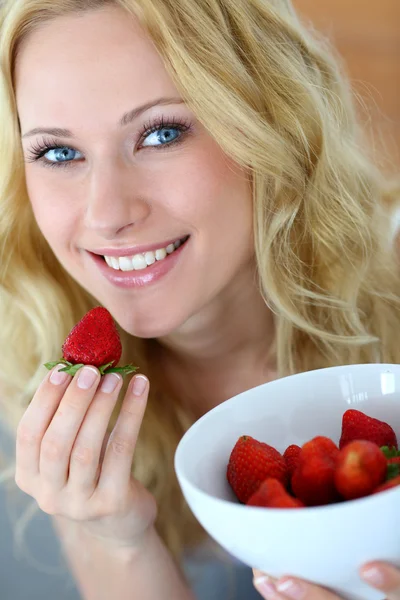 Attractive blong girl eating strawberries — Stock fotografie