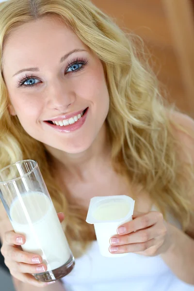 Muchacha atractiva sosteniendo un vaso de leche y yogur — Foto de Stock