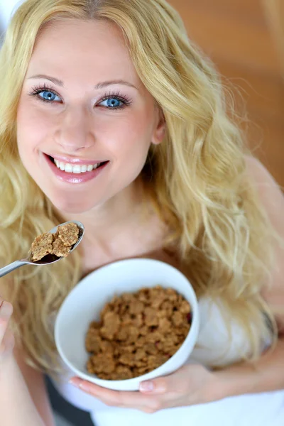 Smiling blond girl eating cereals for breakfast — Stock Photo, Image