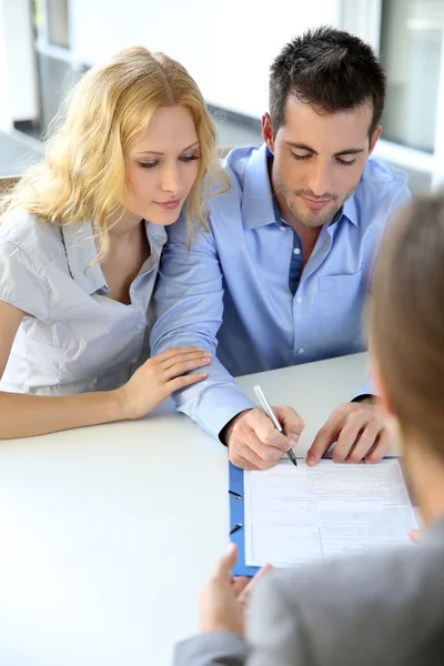 Cheerful couple signing property contract with real-estate agent — Stock Photo, Image