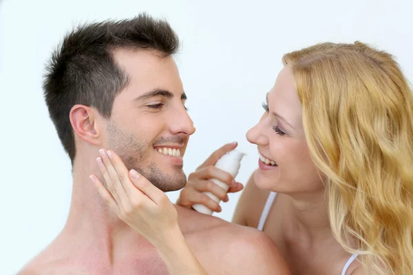 Woman applying sunscreen on her boyfriend's cheeks — Stock Photo, Image