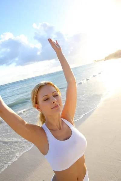 Hermosa mujer haciendo ejercicios de yoga junto a la playa — Foto de Stock