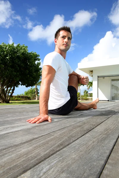 Young man doing stretching exercises by the pool — Stock Photo, Image