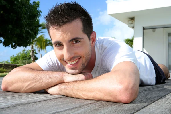 Man relaxing on pool deck after exercising — Stock Photo, Image