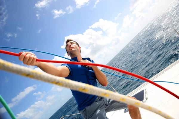 Jovem levantando a vela de catamarã durante o cruzeiro — Fotografia de Stock