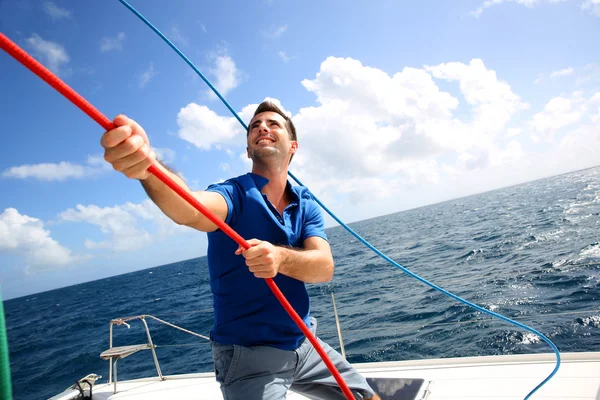 若い男が巡航の間に双胴船の帆を持ち上げる — ストック写真
