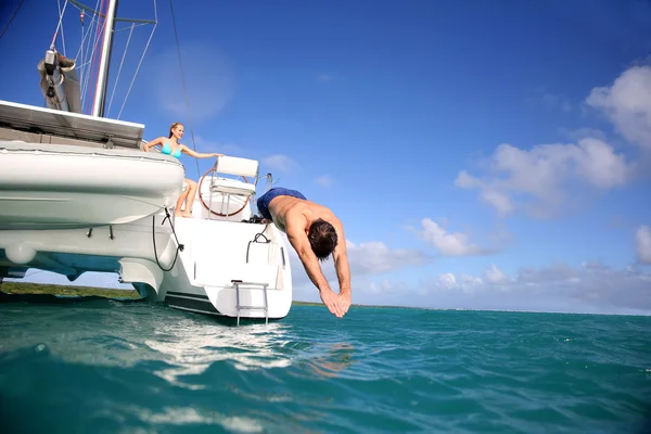 Homem mergulhando do convés de catamarã para o mar — Fotografia de Stock