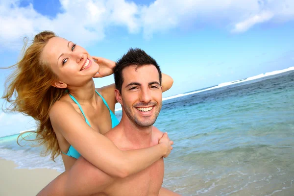 Mann gibt Freundin Huckepackfahrt am Strand — Stockfoto