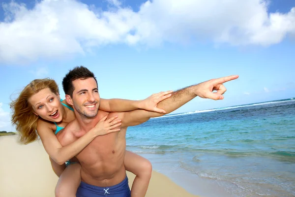 Man geven piggyback rit naar vriendin op het strand — Stockfoto