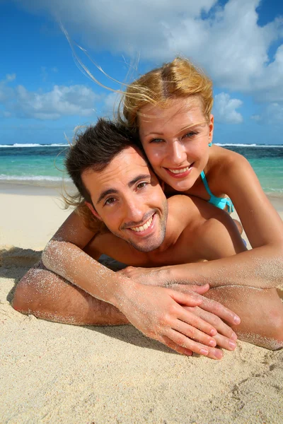 Cheerful young couple laying on a sandy beach — Stock Photo, Image