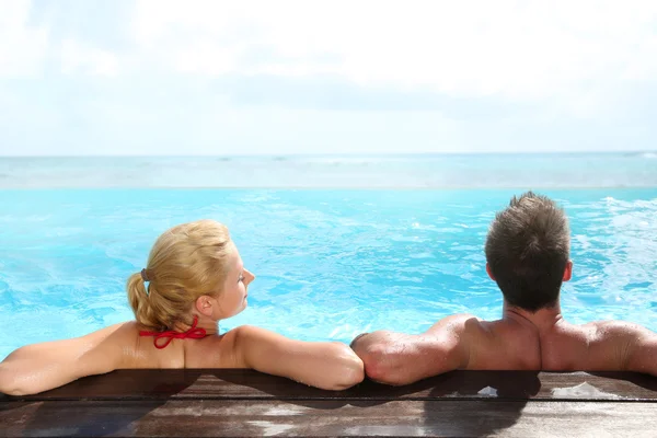 Back view of couple relaxing in swimming pool — Stock Photo, Image
