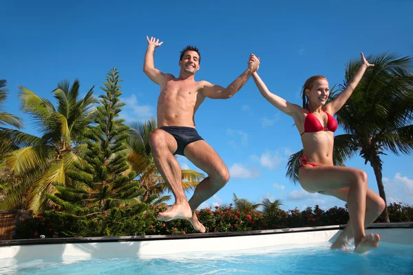Jovem casal pulando na piscina — Fotografia de Stock