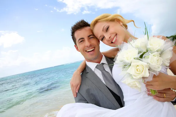 Bräutigam hält Braut am Strand im Arm — Stockfoto