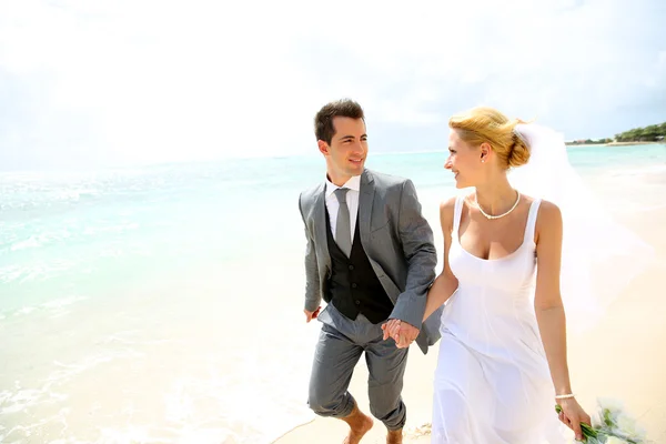 Couple marié courant sur une plage de sable — Photo