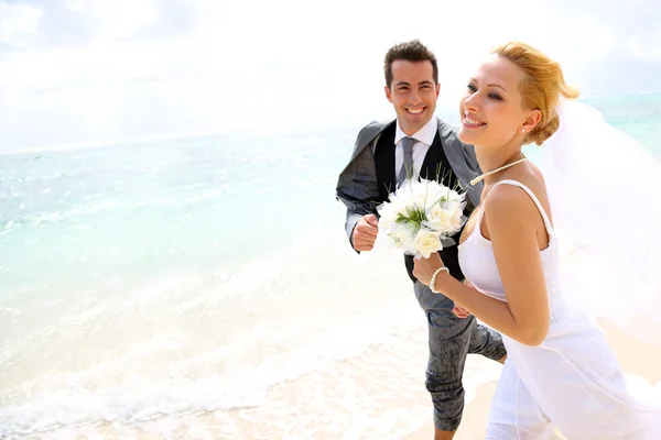 Couple marié courant sur une plage de sable — Photo