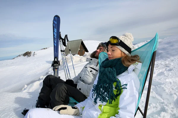 Couple of skiers relaxing in long chairs — Stock Photo, Image